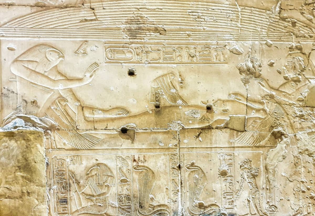 Stone relief showing an ancient Egyptian scene with figures and hieroglyphs, one figure appearing to press on another’s chest.